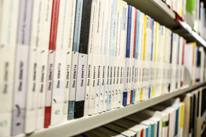 Dissertationen in der Bibliothek Bücher mit der Aufschrift Dissertation auf dem Buchrücken im Bücherregal der Bibliothek
